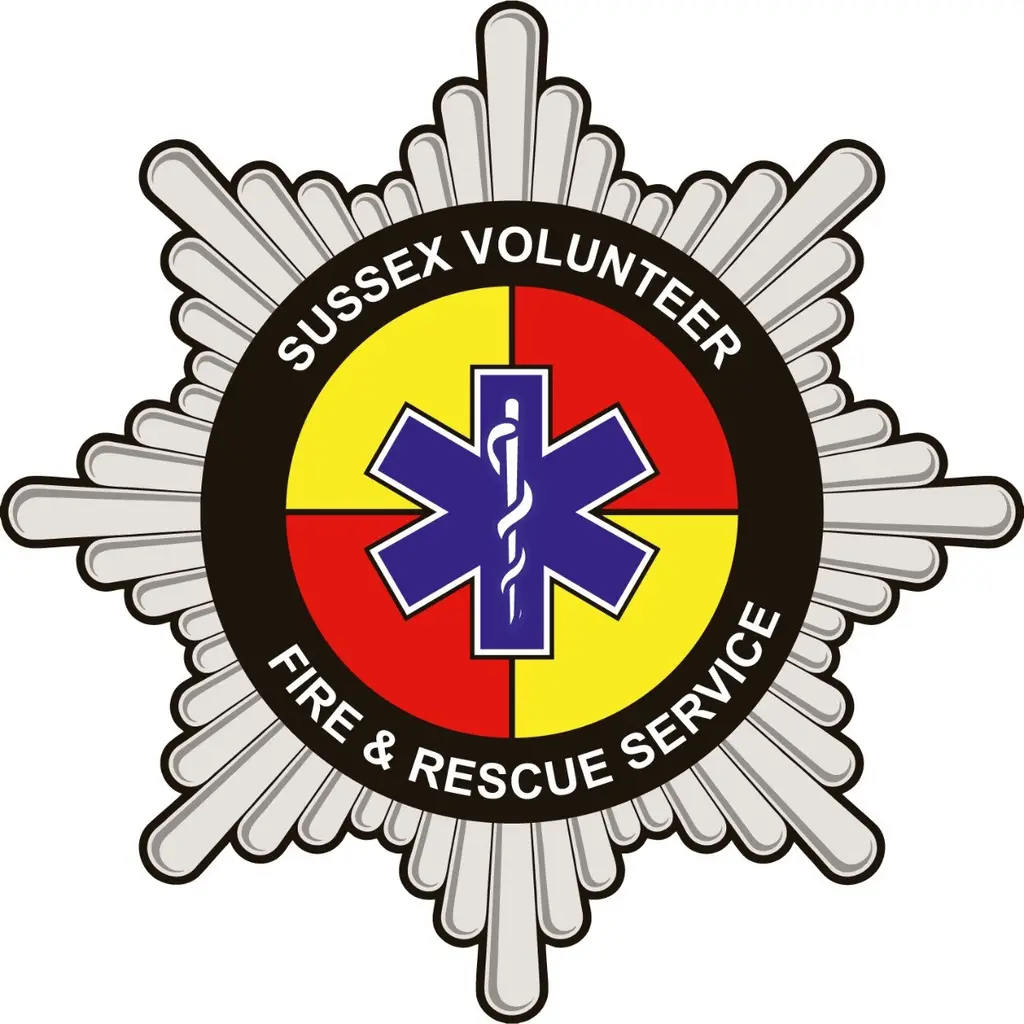 Sussex Volunteer Fire and Rescue badge: a silver fire service star around a black ring, with a red and yellow quartered centre and a blue star of life