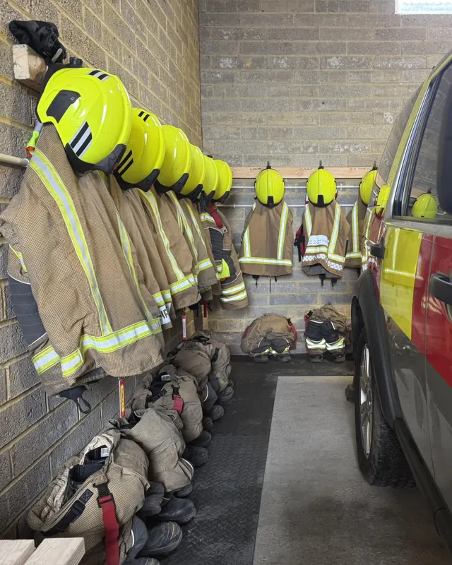 Helmets and fire kit hung ready beside a liveried vehicle