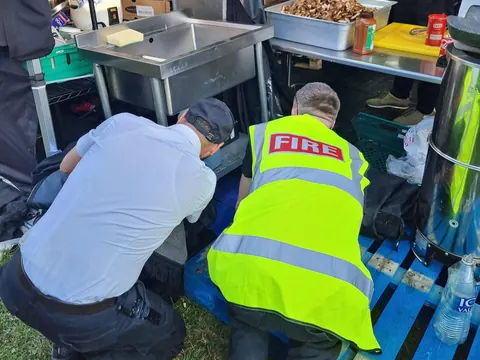 A fire marshal in a hi-vis vest checking a catering stall at an event
