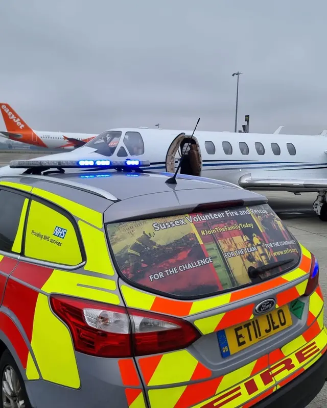 A liveried fire and rescue car with blue lights on an airfield apron